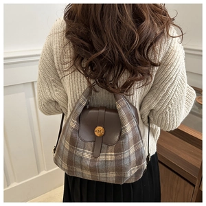 Detail of British style plaid backpack featuring premium leather flap and golden N buckle