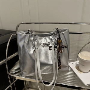 Silver metallic tote bag with crinkled texture, chain strap, and bow detail