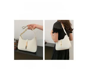 Detailed view of white leather crescent bag with gold chain and adjustable strap