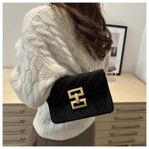 Detail of a black quilted crossbody bag with golden buckle and fine chain strap