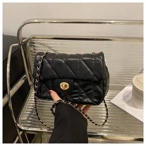 Détail du sac à bandoulière matelassé noir avec chaîne dorée et fermoir pivotant