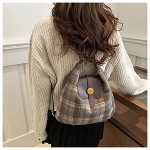 Detail of plaid tote bag with brown leather flap and golden N buckle on model