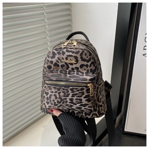Close-up of leopard print mini backpack featuring gold-tone zippers and stylish front metal trim