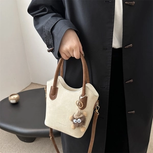 Retro beige tote bag with dark brown handles and cute plush monster charm