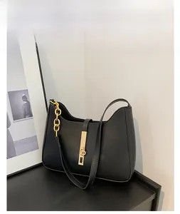 Detail of minimalist black crescent bag with golden chain and metallic buckle accent
