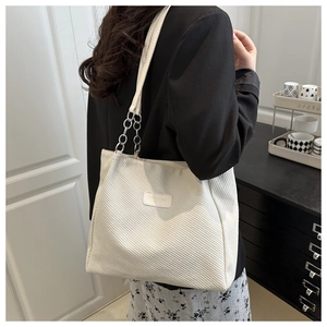 Close-up of cream white chain tote bag with silver metal links and textured fabric finish