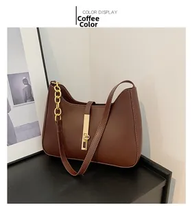 Detail of coffee brown leather crescent bag with golden chain and metallic buckle closure