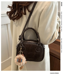 Detail of retro dark brown PU leather handbag featuring embossed lettering and plush lion charm