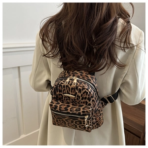 Close-up of leopard print backpack featuring gold metal zippers and canvas straps