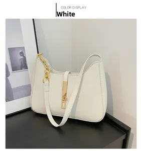 Close-up of a white crescent shoulder bag featuring a gold metal lock and chain strap detail