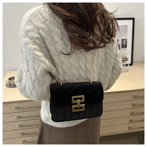 Detail of black velvet crossbody bag with quilted patterns and gold metal chain strap