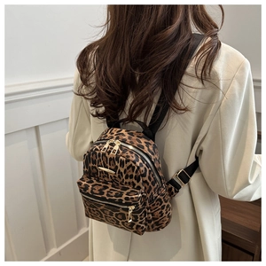 Detail view of mini leopard print backpack with gold hardware on a model's back