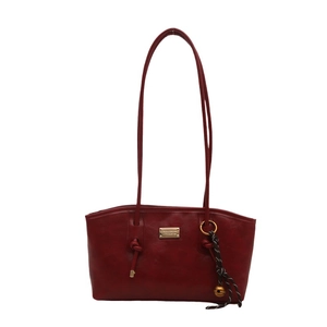 Deep red faux leather shoulder tote bag with gold logo and woven bell charm on white backdrop
