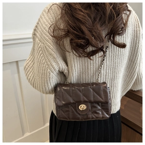 Détail d'un sac à chaîne matelassé marron foncé avec fermoir rotatif doré classique