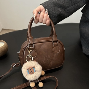 Vintage dunkelbraune Umhängetasche aus Kunstleder mit Prägung und rosa Plüschanhänger