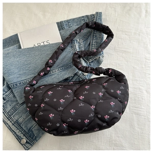 Detailed close-up of black quilted puffer bag with pink floral print and embroidery