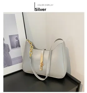 Chic silver underarm bag with gold chain and metal clasp on minimalist black stand
