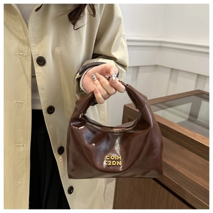 Detail of dark brown hobo bag with oily leather finish and golden logo lettering