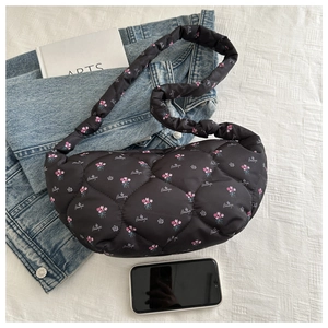 Detail of black quilted nylon croissant bag featuring pink floral print and a phone for scale
