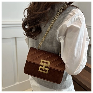 Detail of a brown velvet crossbody bag with V-shaped quilting and a gold chain strap