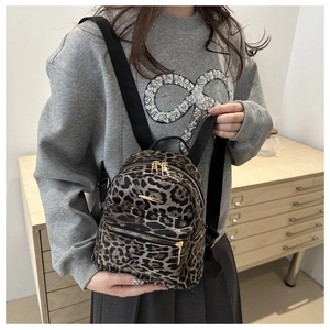 Close-up of leopard print mini backpack featuring golden metal bar and zipper detail