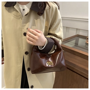 Detail of vintage dark brown glossy leather dumpling bag with brand logo