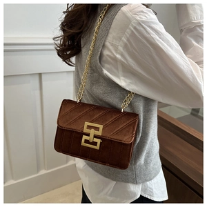 Detail of dark brown velvet crossbody bag with gold chain strap and textured stitching
