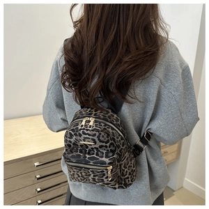 Rear view of a model wearing the mini leopard print backpack with gold zipper details