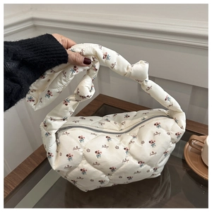 Detailed shot of floral quilted nylon puffy handbag with decorative knot handle design