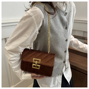 Detail of dark brown velvet crossbody bag with gold geometric buckle and chain strap