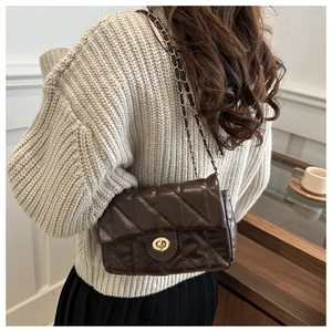 Détail du sac en cuir matelassé marron foncé avec fermoir doré et bandoulière chaîne
