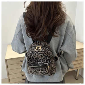 Close-up of leopard print mini backpack with gold hardware worn on a grey hoodie