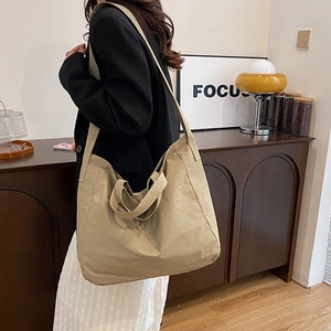 Model carrying a khaki nylon tote bag with handles in a vintage interior setting