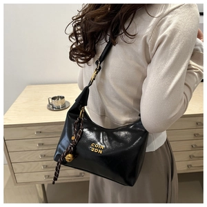 Detail of black semi-circle bag with gold COIH 2DN metal logo and bell charm accessory