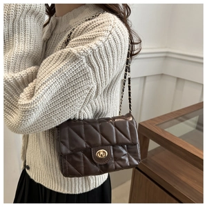 Close-up of brown quilted leather bag with diamond stitching and gold metal twist lock