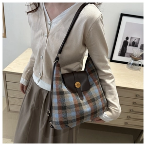 Detail of checkered woolen tote with brown leather flap and golden magnetic N buckle
