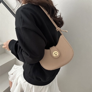 Minimalist beige crescent underarm bag with gold metal buckle shown on a model