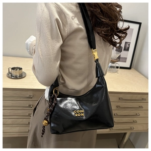 Detail of black crescent shoulder bag with gold metal logo and woven rope charm pendant