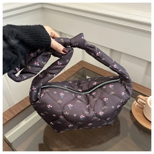 Detail of grey quilted dumpling bag featuring floral print and knotted handle strap