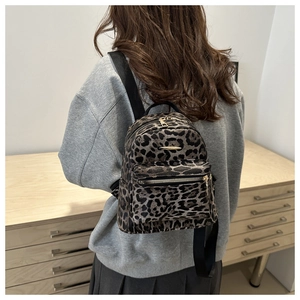 Rear view of a stylish leopard print mini backpack worn by a person in a modern interior