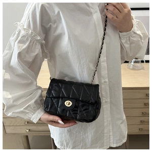 Détails du fermoir doré et de la bandoulière en chaîne du sac matelassé noir