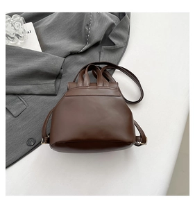 Overhead view of a vintage brown faux leather backpack next to a gray blazer