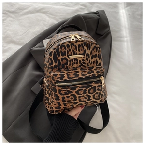 Detail shot of leopard print mini backpack with gold zippers on a grey suit jacket