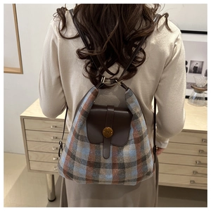 Detail of vintage plaid backpack with leather flap and gold metal buckle on female model