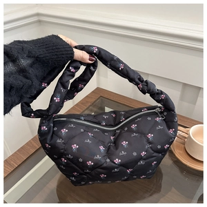 Detail of black quilted nylon hobo bag with small floral print and ruched shoulder strap