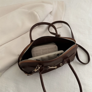 Retro deep brown bowling bag showing large capacity for phone and plaid wallet