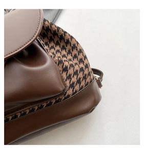 Close-up of vintage houndstooth fabric and brown leather stitching on the backpack