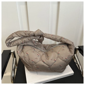 Detail of khaki quilted shoulder bag with floral print and decorative knot handle design