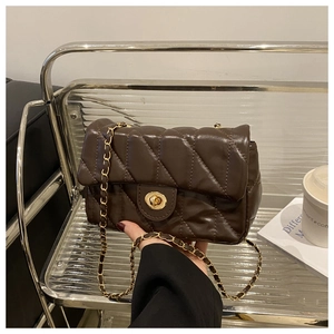 Detail of quilted brown leather crossbody bag with gold chain strap and turn-lock closure