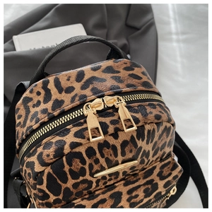Close-up of leopard print backpack showing gold zippers and premium fabric texture